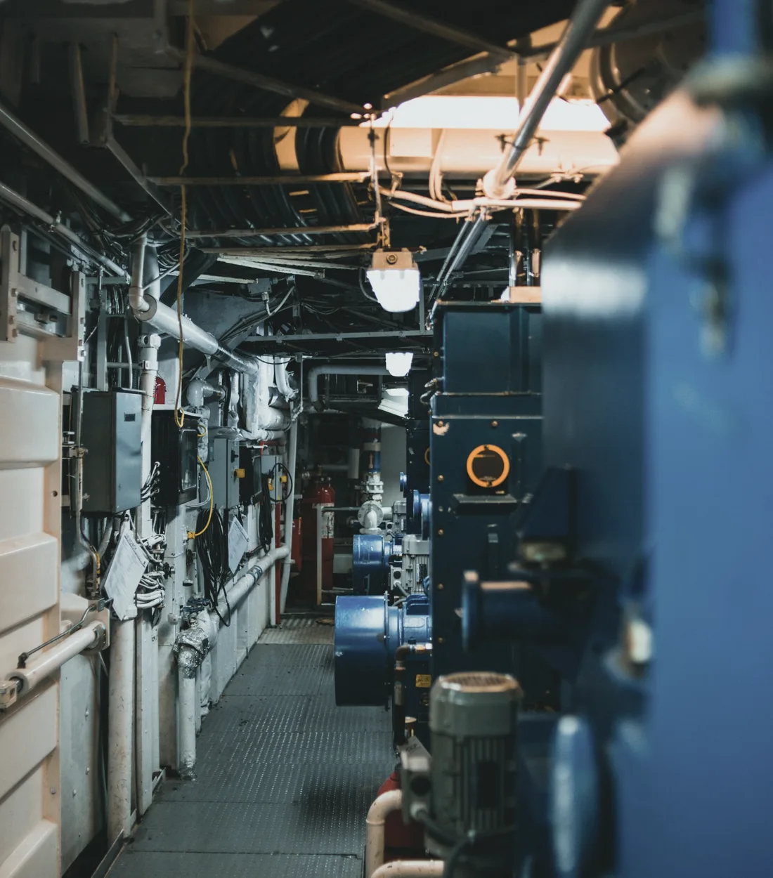 Blue industrial machinery, pipework and valve controls in a plant maintenance corridor